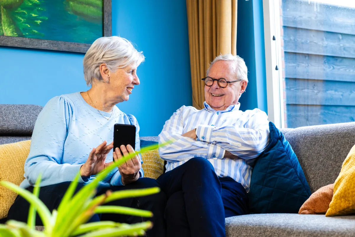 Ouder stel dat samen glimlacht terwijl ze een smartphone vasthouden
